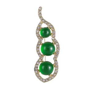 Broche cosse de pois dorée avec trois perles vertes et pavé de cristaux scintillants