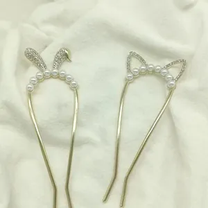 Detail of golden U-shaped hair pins with pearls and rhinestones in bunny and cat shapes