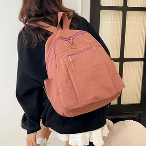 Vista posteriore di uno zaino in nylon rosa antico con tasche a zip su felpa nera