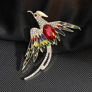 Detalle de un broche de fénix con alas de esmalte de colores e incrustación de piedra roja