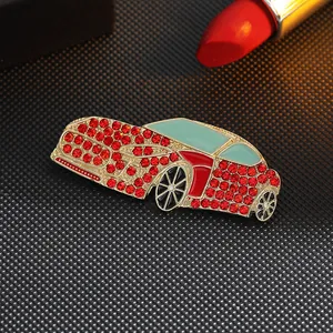 Macro detail of red rhinestone car brooch with gold finish and blue enamel on black fabric