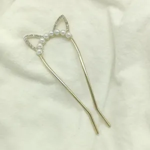 Macro detail of U-shaped gold hairpin with cat ear design, pearls and crystals
