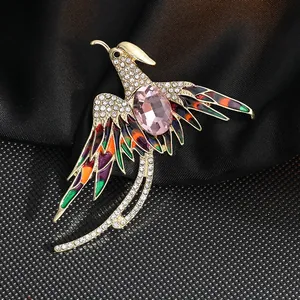 Detalle de un broche de fénix con alas de esmalte colorido y una piedra preciosa rosa