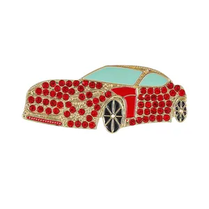 Golden sports car brooch with red rhinestones and green enamel windows on white background