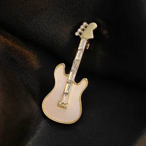 Elegant gold electric guitar brooch with white inlay and sparkling crystals on silk background