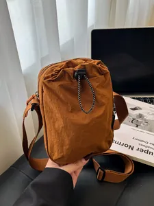 Waterproof brown nylon crossbody bag with drawstring front pocket and adjustable strap