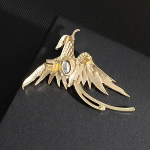 Detalle de la parte posterior del broche de fénix dorado con textura y cierre de seguridad
