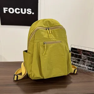Dettaglio dello zaino in nylon giallo senape con trama premium e tasca frontale con zip
