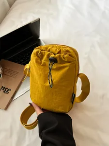 Waterproof yellow nylon mini crossbody bag with drawstring detail and adjustable strap