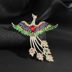 Detalle de broche de fénix con alas de esmalte colorido y piedra roja en forma de pera