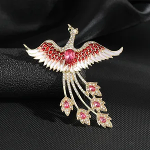 Detalle macro de broche de fénix con cristales rojos y esmalte blanco en seda negra