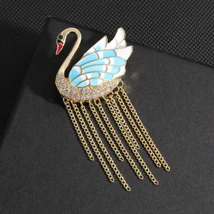 Elegant swan brooch with blue enamel wings, sparkling rhinestones and golden tassels