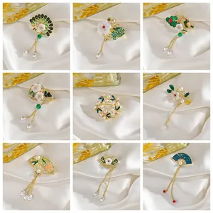 Broches dorados orientales con flores esmaltadas, perlas y borlas en fondo de seda