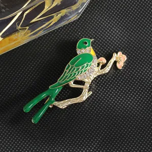 Detalle del broche de fénix con esmalte verde, flores rosas y brillantes pedrería