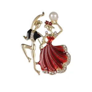 Élégante broche couple dansant dorée avec robe en émail rouge et perle sur fond blanc