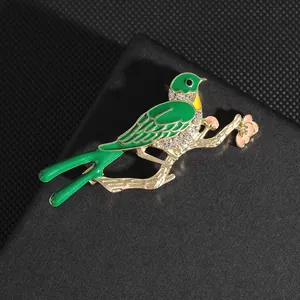 Detalle de broche de pájaro en esmalte verde con cristales y flores en metal dorado