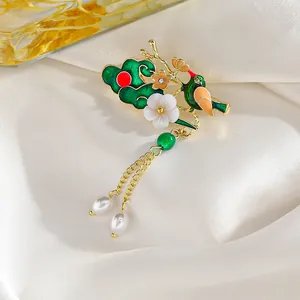 Detalle del broche esmaltado vintage con pájaro, flor, borlas doradas y perlas