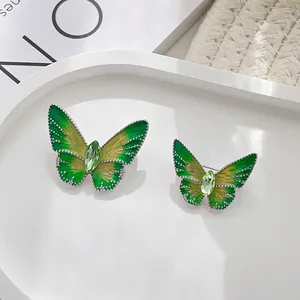 Macro detail of enamel butterfly brooches with green olive crystal and gradient wings