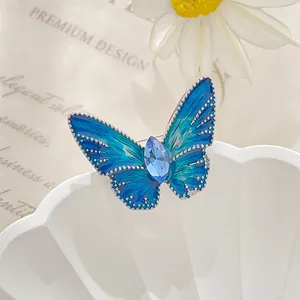 Macro detail of enamel butterfly brooch with blue gradient wings and gemstone inlay