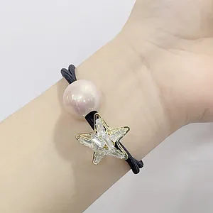 Detail of elastic hair tie featuring a golden starfish pendant with crystals and pearl