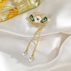 Primer plano de un broche dorado de estilo chino con pétalos verdes y borlas de perlas