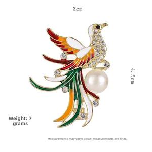Detalle de broche de fénix esmaltado con pedrería de colores y perla blanca