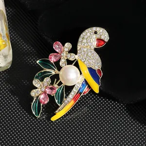Detalle macro de un broche de loro con plumas de esmalte y una perla grande