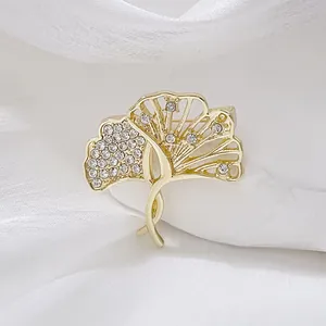 Broche élégante en forme de feuille de ginkgo dorée ornée de strass sur fond de soie