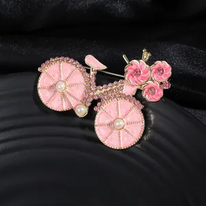 Dettaglio della spilla a forma di bici in smalto rosa con strass e perle preziose