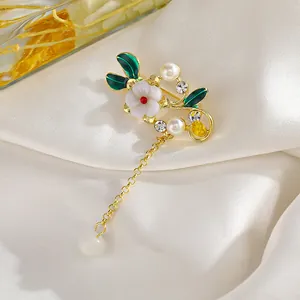 Detalle del broche de flor vintage con hojas de esmalte verde, perlas y borla colgante