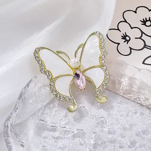 Detail einer Schmetterlingsbrosche mit rosa Kristall, weißen Flügeln und Strass