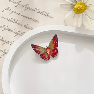 Detailed macro view of the butterfly brooch with red enamel wings and ruby core crystal