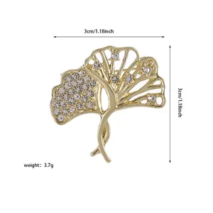 Détail de la broche feuille de ginkgo dorée ajourée avec strass blancs étincelants