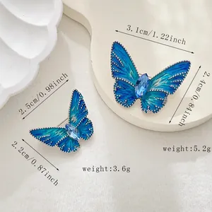Detail showing two gradient blue butterfly brooches with silver beaded edges and gems