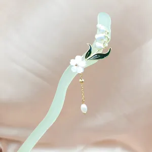 Eleganter Haarstab mit hellgrüner Harzwand, Blumen und Perlenquaste auf Satinhintergrund