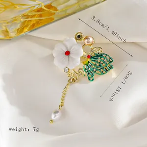 Primer plano de broche de mariposa verde con perla sobre tela de seda blanca