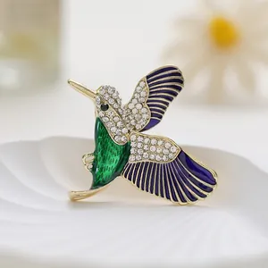 Broche colibri élégante avec émail coloré, strass blancs et finition plaquée or