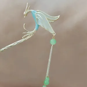 Detail of a golden phoenix hair pin with blue enamel wings and green beaded tassels
