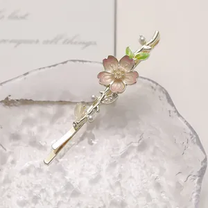 Elegant pink cherry blossom hair clip with pearls and green leaves on glass base