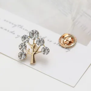 Detailed view of tree brooch with gold base and six sparkling round crystals