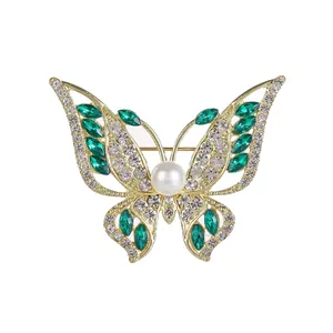 Elegant gold butterfly brooch featuring green marquise gems and a center pearl detail