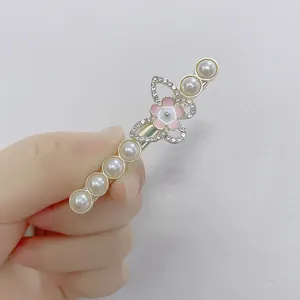 Détail d'une barrette à cheveux avec perles blanches et ailes de papillon en strass