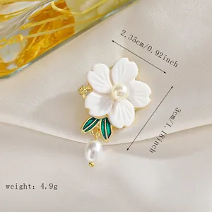 Vista detallada del broche de flor con hojas verdes y medidas 2,35 cm por 3 cm
