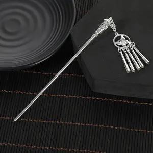 Macro detail of silver ethnic hair stick featuring hollow butterfly ring and metal tassels