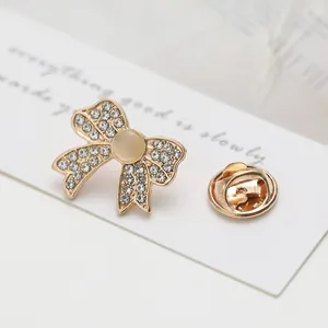 Macro detail of golden bow brooch with sparkling rhinestones and a central opal stone