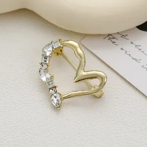 Élégante broche cœur dorée avec cristaux étincelants sur un fond texturé minimaliste