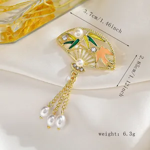Detalle de broche en forma de abanico con esmalte de bambú y borlas de perlas largas