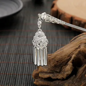 Macro shot of silver hair pin featuring intricate hollow patterns and hanging tassels
