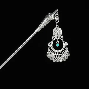 Detail of vintage silver hair pin with hollow pattern, turquoise bead and tassels