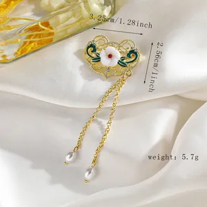 Detalle de broche floral dorado con esmalte verde, perlas y dimensiones en seda